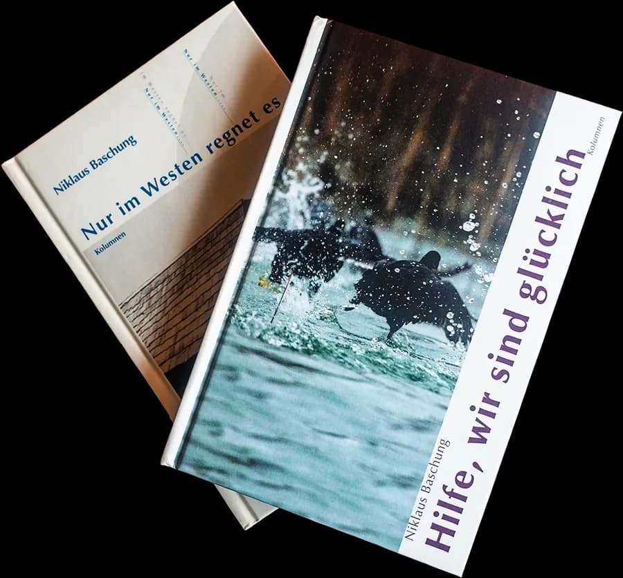 Zwei Bücher nebeneinander auf einem dunkelroten Tisch