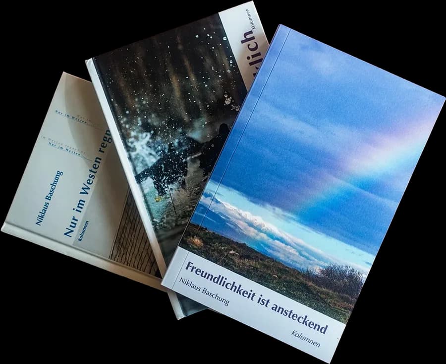 Drei Bücher übereinander auf einem dunkelroten Tisch